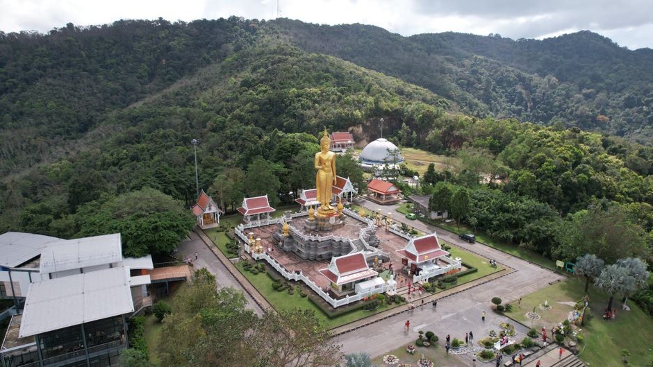 Aerial view of a golden Buddha statue in a lush mountainous Thai landscape, offering a serene ambiance. (photo by mohd hasan on Pexels)