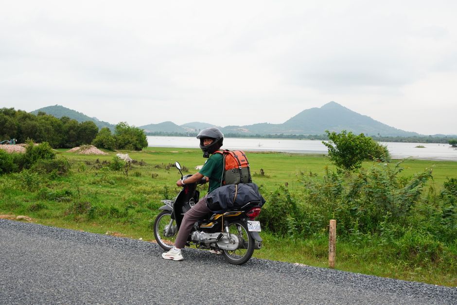 Traveler on a motorbike exploring the scenic landscape of Kampot, Cambodia, with lush greenery and mountains. (photo by So Phors on Pexels)