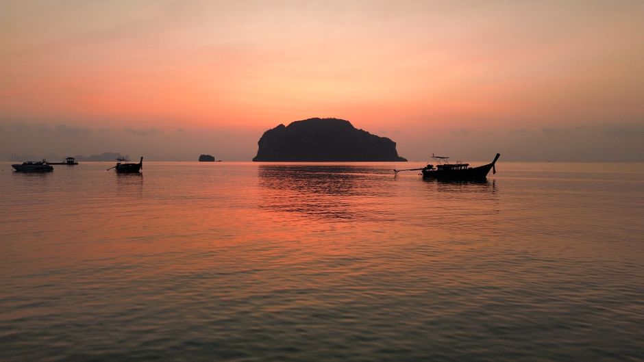 Peaceful sunrise over Phang Nga Bay in Thailand with silhouetted boats and islands. (photo by mirthe diender on Pexels)