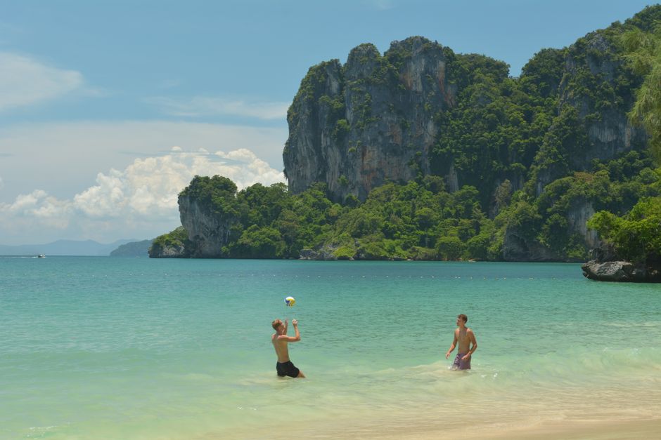 Two men enjoy a game of beach volleyball on Ao Nang's sandy shores with stunning limestone cliffs in the background. (photo by Александр on Pexels)