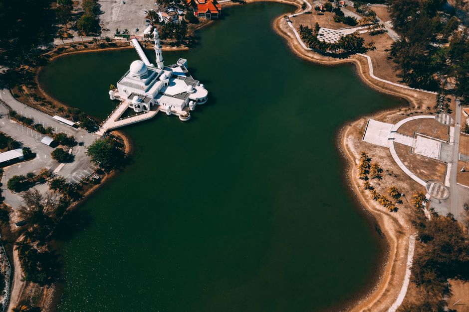 Stunning aerial view of an isolated mosque on a tranquil lake island with surrounding landscape. (photo by Pok Rie on Pexels)