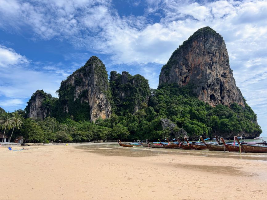 Scenic view of limestone cliffs and longtail boats at Railay Beach, Krabi, Thailand on a sunny day. (photo by Ines Diaz Cervantes on Pexels)