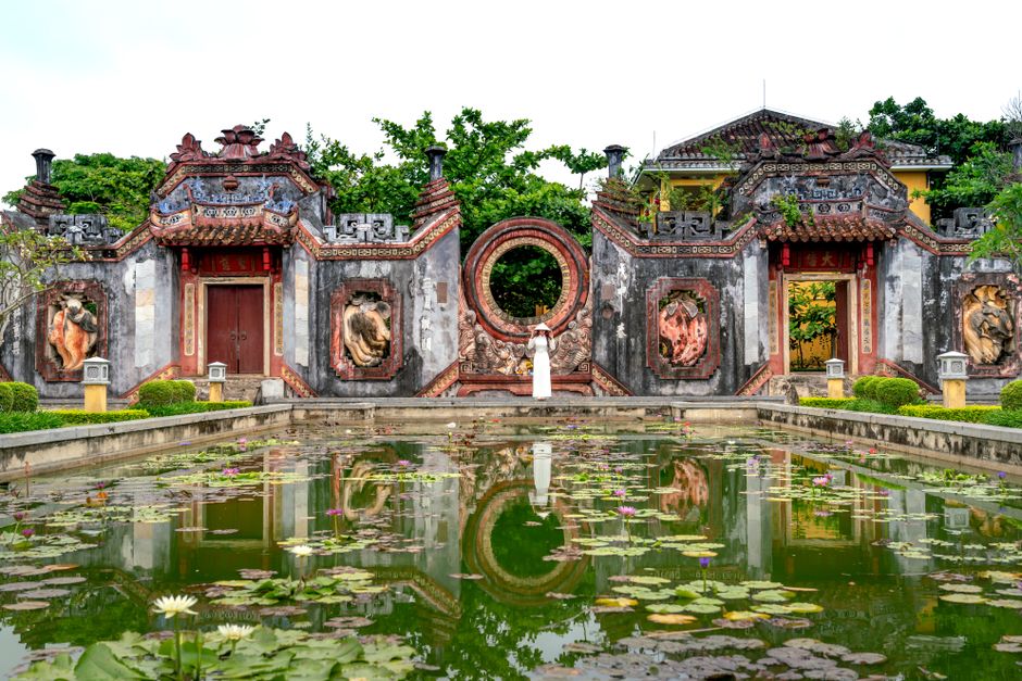 Scenic view of a historic temple facade with a tranquil pond and lotus flowers. (photo by Quang Nguyen Vinh on Pexels)